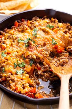 a skillet filled with some taco meat and tortilla chips on the side