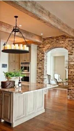 a large kitchen with an island in the middle and candles hanging from it's ceiling