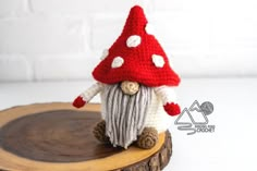 a crocheted gnome sitting on top of a tree stump