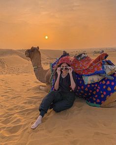 a woman sitting on top of a camel in the desert