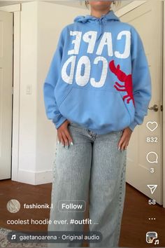 a woman wearing a blue hoodie with the words cape cod on it, standing in front of a door