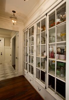 an old fashioned china cabinet with glass doors and shelves in the middle of a hallway