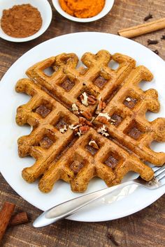 a white plate topped with waffles next to bowls of powdered sugar and cinnamon