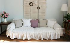 a white couch with pillows on it in front of a wooden headboard and window