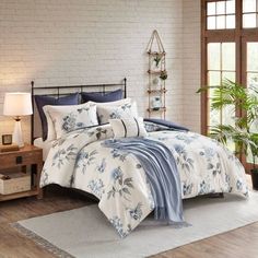 a bed with blue and white comforters in a room next to a window,