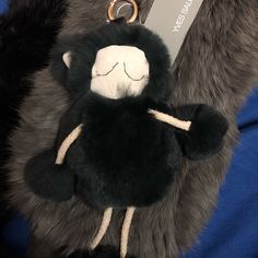 a black and white stuffed monkey keychain on a blue blanket with a tag attached to it