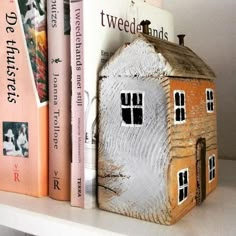 a book shelf with books and a small house on it