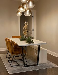 a dining room table and chairs with lights hanging from the ceiling