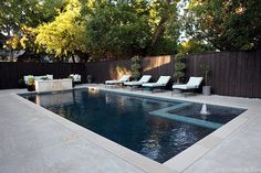 an outdoor pool with lounge chairs around it