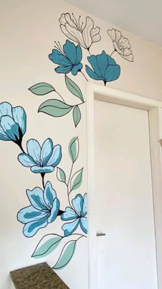 a white door sitting next to a wall with blue flowers painted on it's side