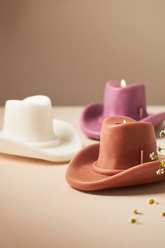 three different colored hats sitting on top of a table next to candles and confetti