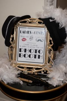 a black and white photo frame with feathers around it on top of a small table