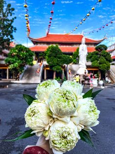 a person holding a bouquet of flowers in front of a building