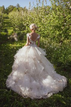 a woman in a wedding dress walking through an apple orchard