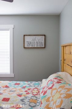 a bed sitting under a window next to a wooden dresser