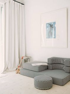 a living room with white walls and black and white striped furniture in front of a large window