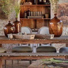 a wooden table topped with vases sitting next to a book shelf filled with books