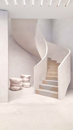 a white staircase in an empty room with bowls on the floor