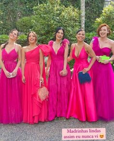 four women in bright pink dresses posing for a photo with one woman holding a purse