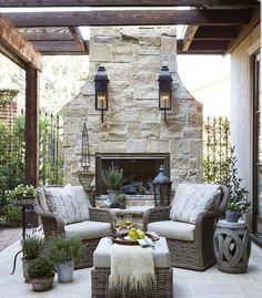 an outdoor living room with stone fireplace and wicker furniture