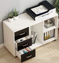 an office desk with two drawers and a file cabinet on the bottom, next to a potted plant