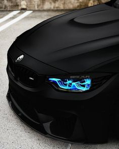 the front end of a black bmw car with blue lights on it's hood