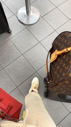 the legs of a person standing next to luggage and bags on the floor at an airport