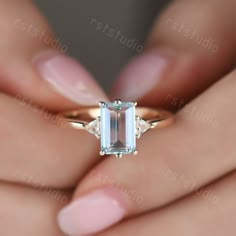 a woman's hand holding an emerald and diamond ring