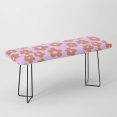 a pink bench with flowers on it and black metal legs, against a white background