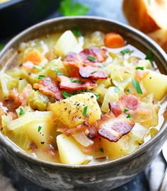 a close up of a bowl of food with potatoes and bacon in it on a table