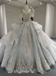 Delve into the dream of a fairytale wedding with this enchanting gown, where every stitch tells a story of romance and sophistication! The dress begins with a bodice lavishly encrusted with crystals and pearls, sculpting a figure of noble grace. The sleeves, a cascade of gossamer tulle, drape elegantly to reveal a hint of the shoulders, balancing allure with modesty. As the eye travels down, the skirt blooms into an extravagant display of layered lace, embroidered with meticulous care to create patterns that are both timeless and mesmerizing. This gown is finished with a train that commands the room, ensuring that your every step is nothing less than regal. Itmore than a wedding dress; ita symbol of love's grandeur, awaiting a bride who is ready to shine on her most cherished day. Elegant Poofy Wedding Dress, Winter Wonderland Wedding Dress Gowns, Ball Room Wedding Dress, Wedding Dresses No Sleeves, Older Wedding Dress, Queen Dresses Royal, Bride Dress Unique, Fancy Princess Dresses, Fairy Princess Wedding Dress