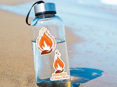 a water bottle with a sticker on it sitting in the sand at the beach