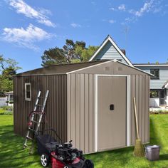 a garden shed with a lawn mower and tools in the grass next to it