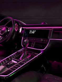 the interior of a car is lit up with purple lights and features an electronic clock