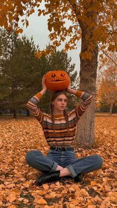 a woman sitting on the ground with her head in a jack - o'- lantern hat