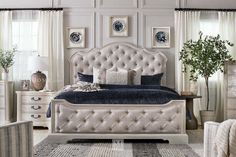 a white bed sitting in a bedroom next to two chairs and a table with a potted plant on top of it