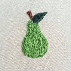 an embroidered pear on a white surface