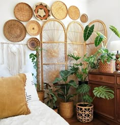 a bedroom with lots of plants and wicker baskets on the wall above the bed