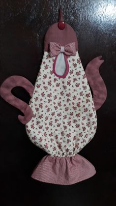 an oven mitt with a bow on it and pink flowers in the front, sitting on a black surface