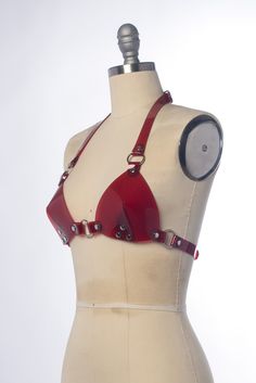 This harness bra top is designed to be either a layering piece or one of those tops that intentionally don't contain and cover everything. Super hot! Halter style straps. Buckles in front, back, and behind the neck. Silver-toned nickel plated hardware. Shown in black PVC and translucent red PVC. Also available in black leather, black vegan leather, and more! Pairs well with the pvc harness thong/bottom frame (shown in the last photo), available separately. ** This is sized according to the size Party Bra With Adjustable Straps And Triangle Top, Party Triangle Top Bra With Adjustable Straps, Edgy Party Harness With Straps, Punk Style Harness For Night Out, Fitted T-back Bra With Straps, Party Backless Bra With Straps, Fitted Strapped Harness For Party, Fitted Strappy Bra With Multiple Straps, Fitted Multiple Straps Strappy Bra