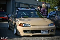 a beige car with skis on top parked in a parking lot