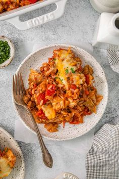 a bowl filled with pasta and cheese on top of a white table next to other dishes