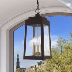 a lantern hanging from the ceiling in front of a window with trees and buildings outside