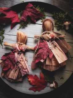 three wooden dolls made out of leaves on a table