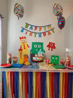 a birthday party with colorful streamers, decorations and paper cutouts on the table