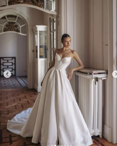 a woman in a white wedding dress leaning against a wall