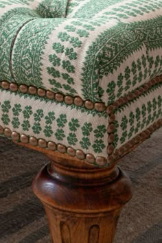 a green and white ottoman sitting on top of a wooden table next to a rug