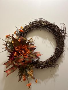 a wreath with orange and yellow flowers hanging on the wall next to a white wall