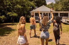 several people standing in front of a house with one woman raising her arms up to the sky