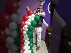 a man standing next to a balloon arch